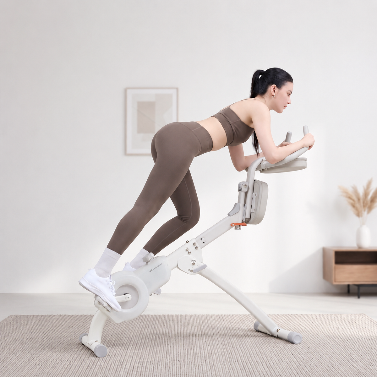 女性在明亮居家客廳以核心登山車模式使用 Wonder Core Flex Cycle 2 霜霧白翻轉健身車，前臂靠肘墊、上身前傾踩踏，示範居家飛輪健身車的二合一核心訓練姿勢