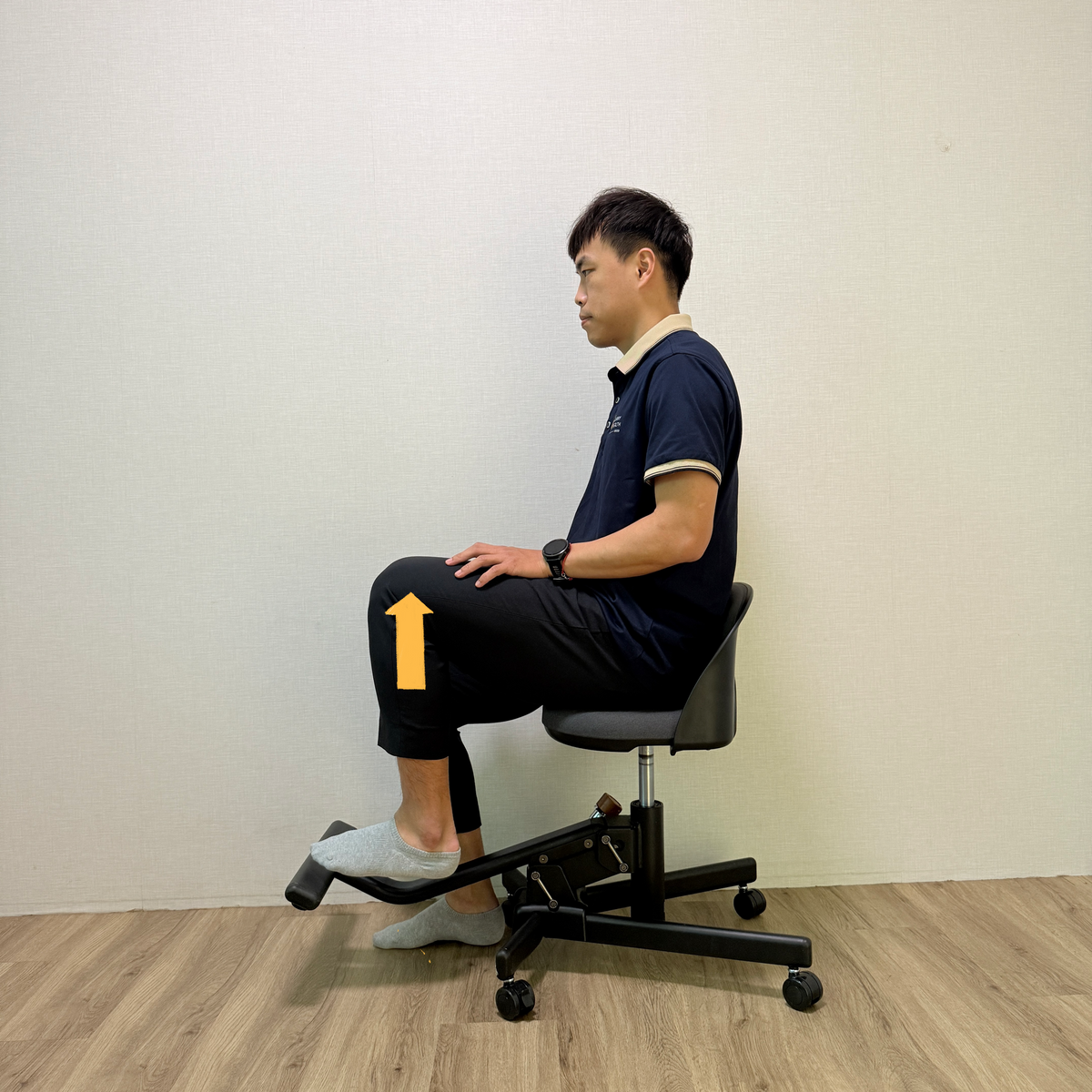 男性側坐 Wonder Core Chaircise 核心喚醒工學椅、單腳下踩踏板，黃色箭頭標示發力方向，久坐腰痠主動核心訓練