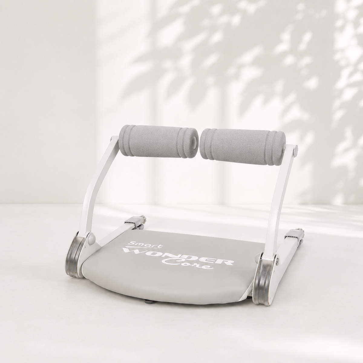 Wonder Core Smart 健腹器（星霧灰）展開於明亮居家地板，灰色泡棉握把與專利彈簧結構，2026 居家健腹器推薦首選