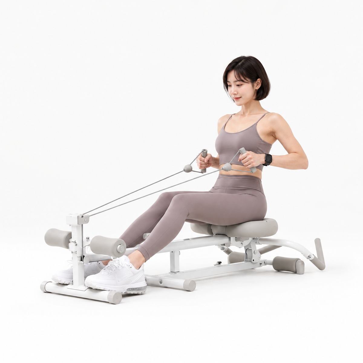 女性穿藕紫色運動服坐在白色 Wonder Core Pro Max 四合一健身機上做划船動作、雙手拉繩，示範新手居家划船機的正確姿勢訓練